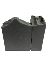 Load image into Gallery viewer, Coconut oil, rspo palm oil, canola oil, organic olive oil,organic avocado, castor oil, aloe vera juice, kaolin clay, vegan coconut milk powder, activated charcoal, citric acid (natural preservative), sugar, and essential oil blend. Intoxicating smells like Bourbon with top notes of Rose, middle notes of Wood and bottom notes of Sandalwood and Tonka Bean. This bar is a good for all skin types, helps balance your skins ph and exfoliants.